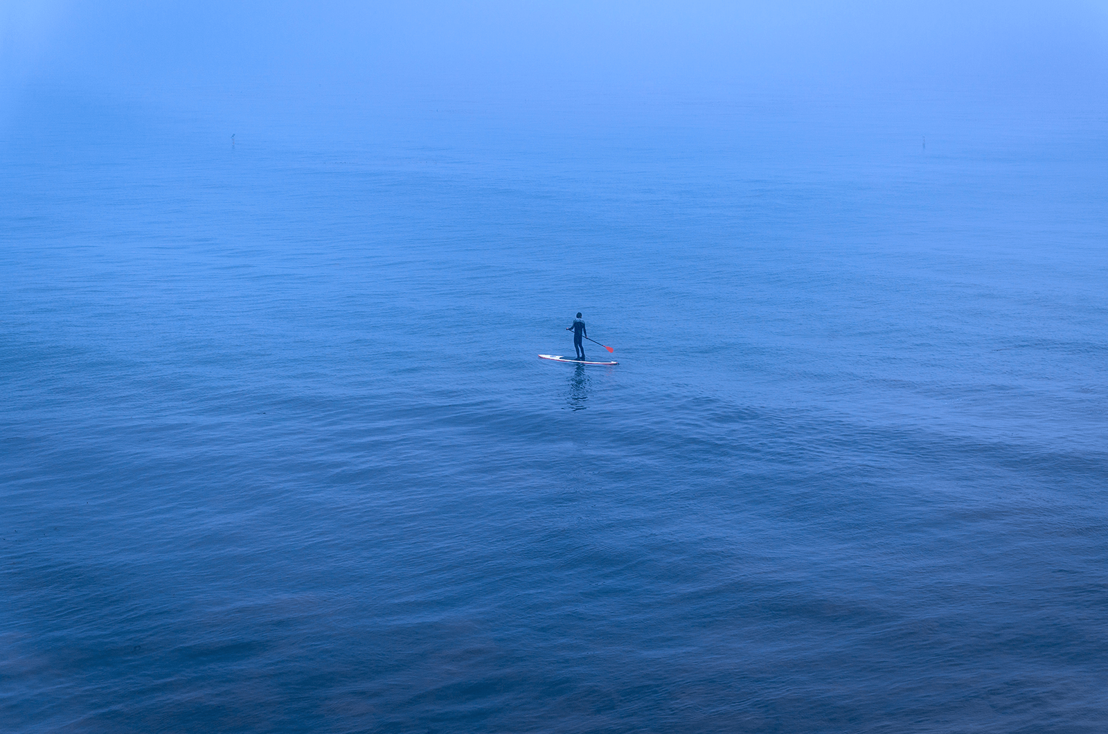 Man paddling a canoe in blue water