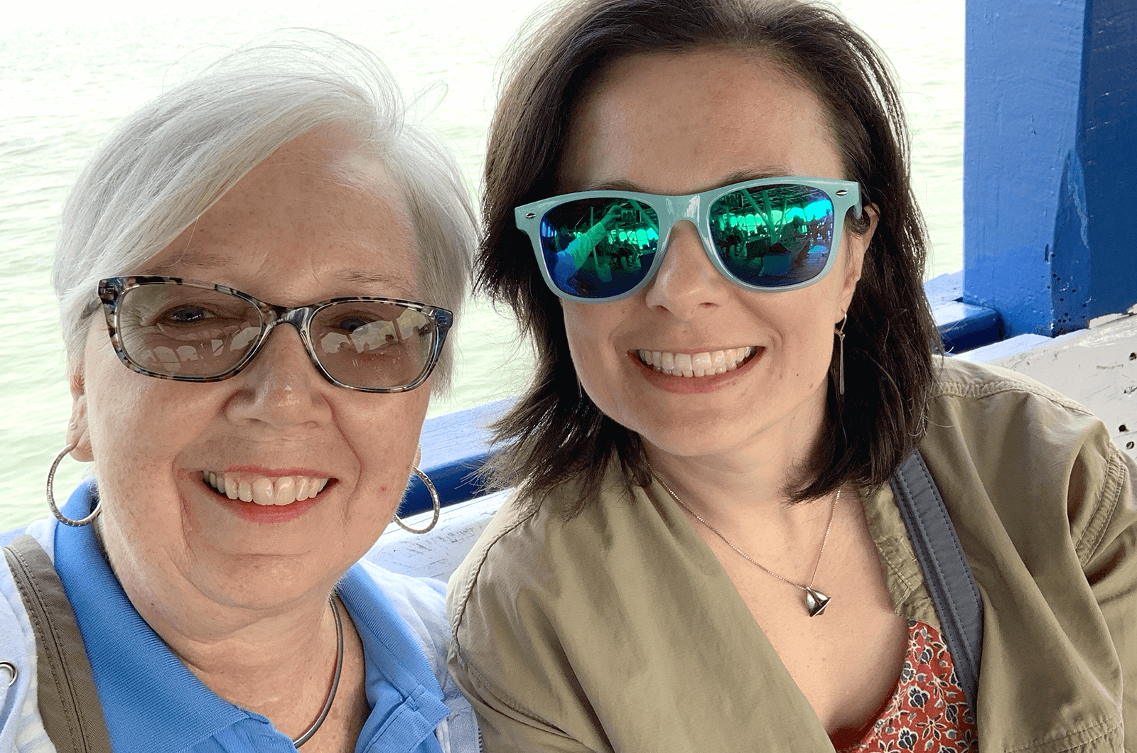 Two women posing and smiling wearing sunglasses