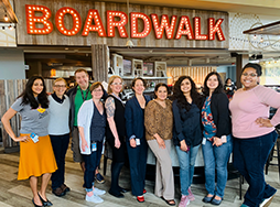Group of people posing under lit up boardwalk sign