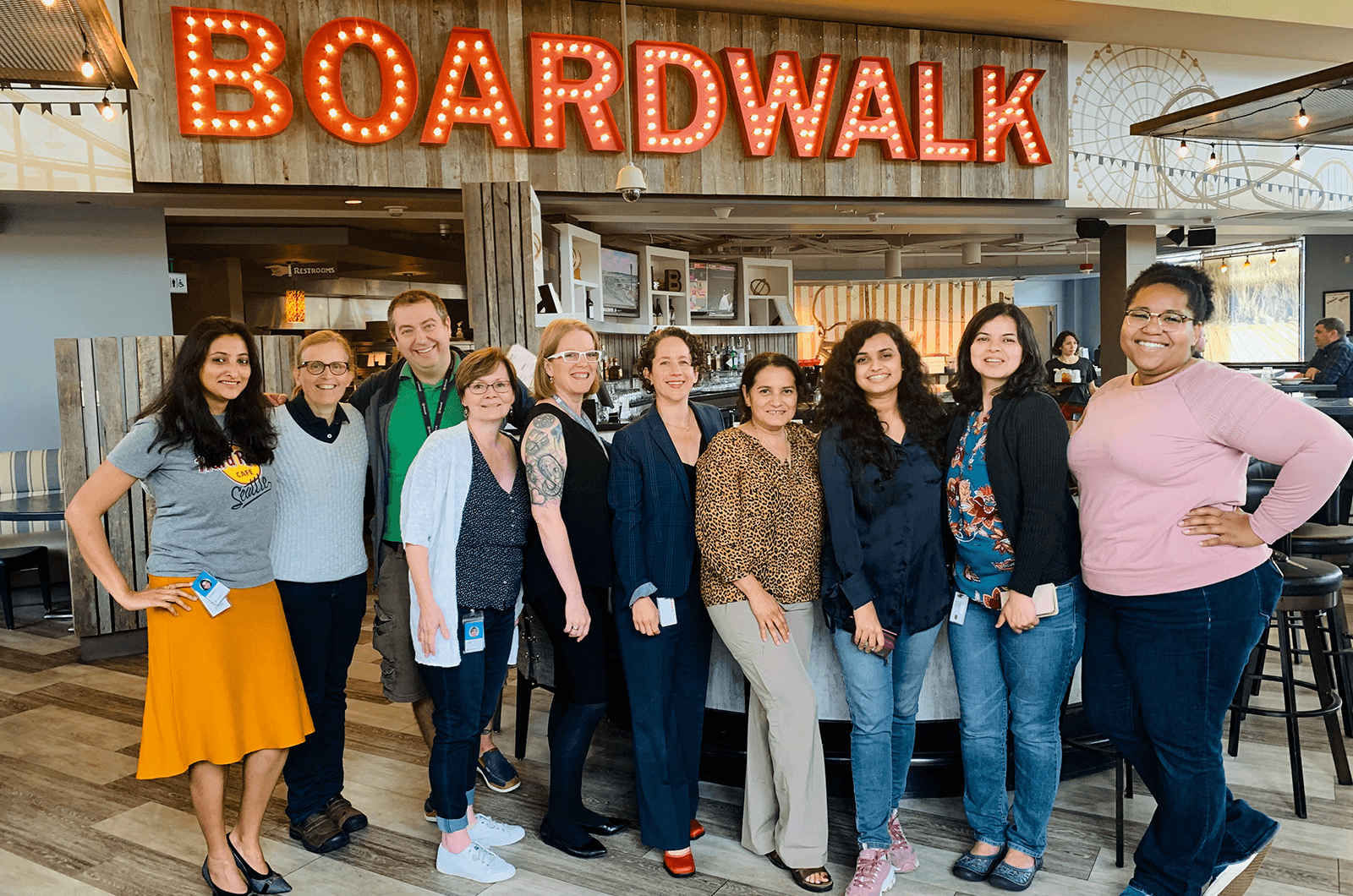 Group of people posing under lit up boardwalk sign