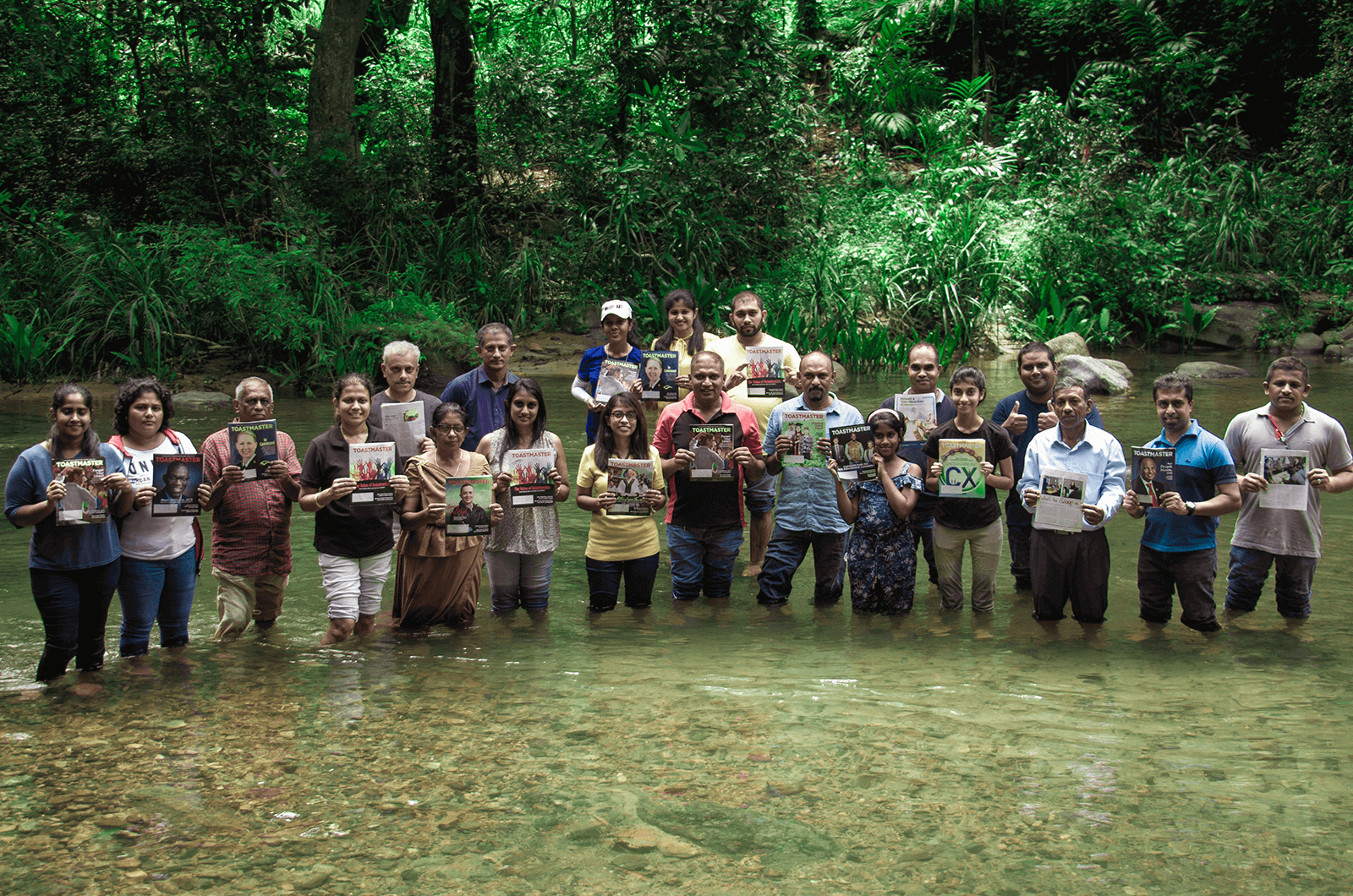 Group of people standing in a stream with Toastmaster magazines