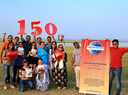 Group of people posing outdoors with banner and cut out numbers 150