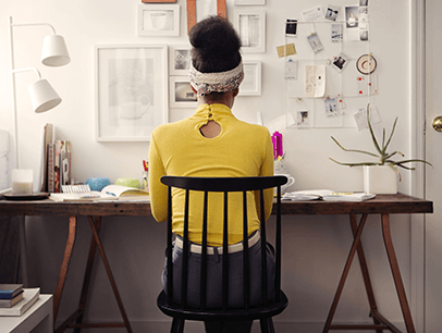Woman in yellow sweater working at desk at home