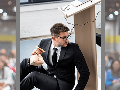 Man hiding behind lectern peeking out at audience