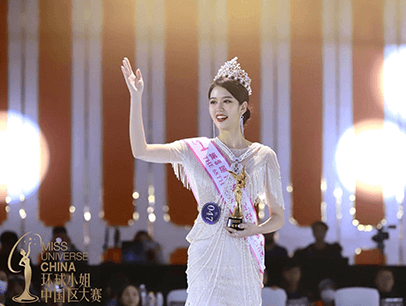 Woman wearing crown and waving onstage