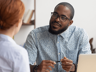 Man with glasses speaking to woman