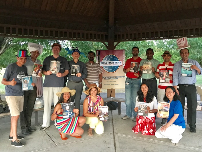 Members of State Street Princeton Toastmasters  club in Plainsboro, New Jersey, celebrate the end of summer with an outdoor meeting, some silly hats, and their Toastmaster magazines.